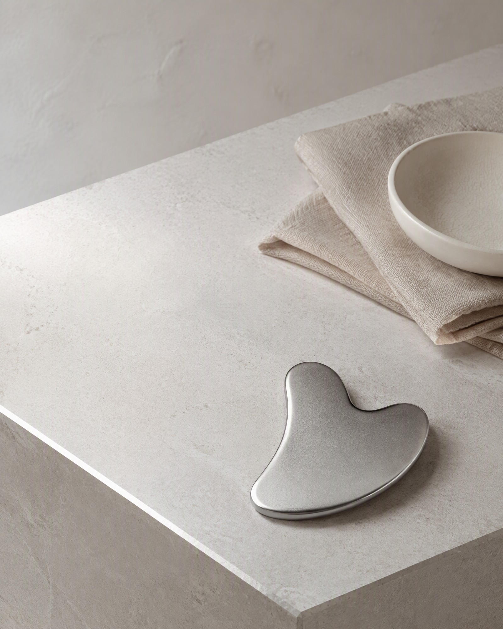 Cosmetic gua sha and facial massage accessories on a clean stone surface