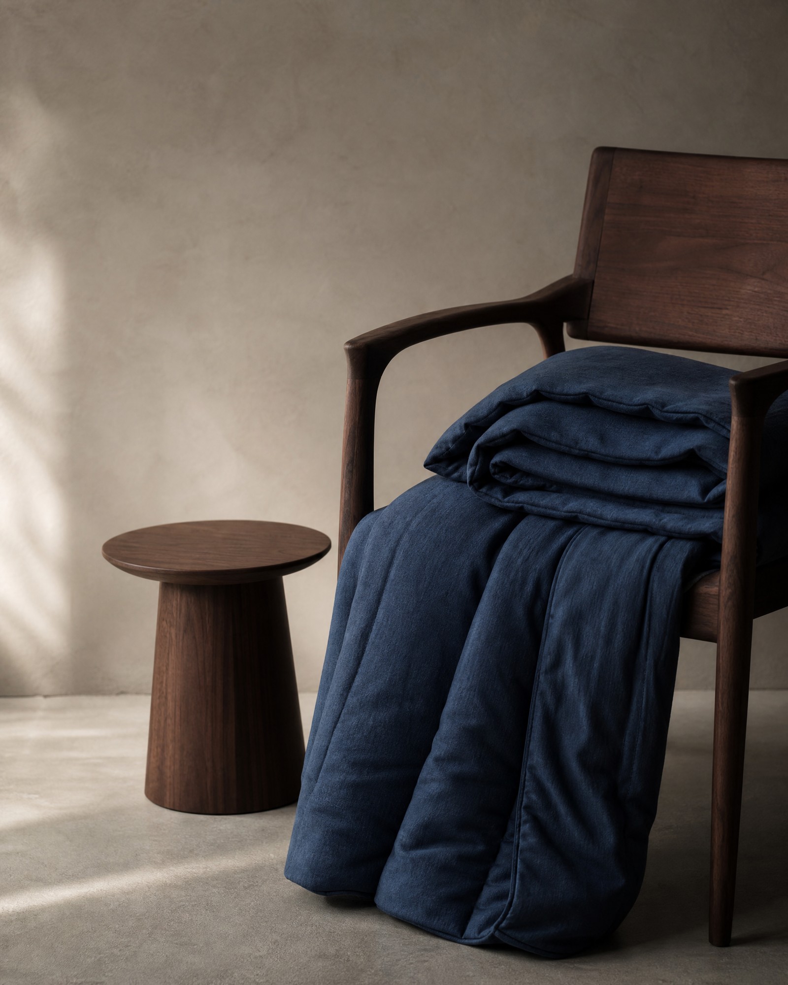 Folded weighted blanket and quiet reading corner in cool neutral tones
